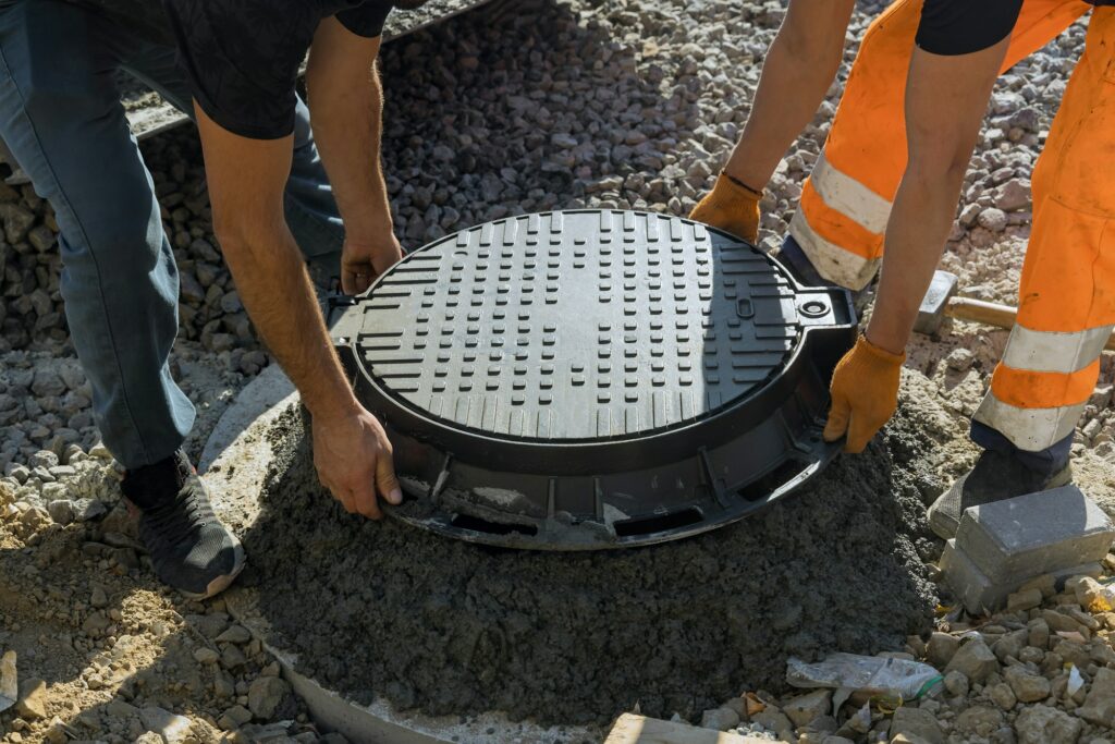 A worker installs a sewer manhole on a septic tank made of concrete rings